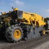 A yellow XCMG road cold recycler performing Cold In-Place Recycling (CIR) on a highway rehabilitation project to drastically reduce construction costs.