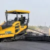 An XCMG RP1355 asphalt paver machine operating on a road construction site, representing the ultimate buying guide for paving equipment.
