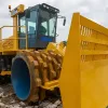 A yellow XH263J heavy-duty landfill compactor with spiked wheels and a large front blade working on a solid-fill construction site under a cloudy sky.