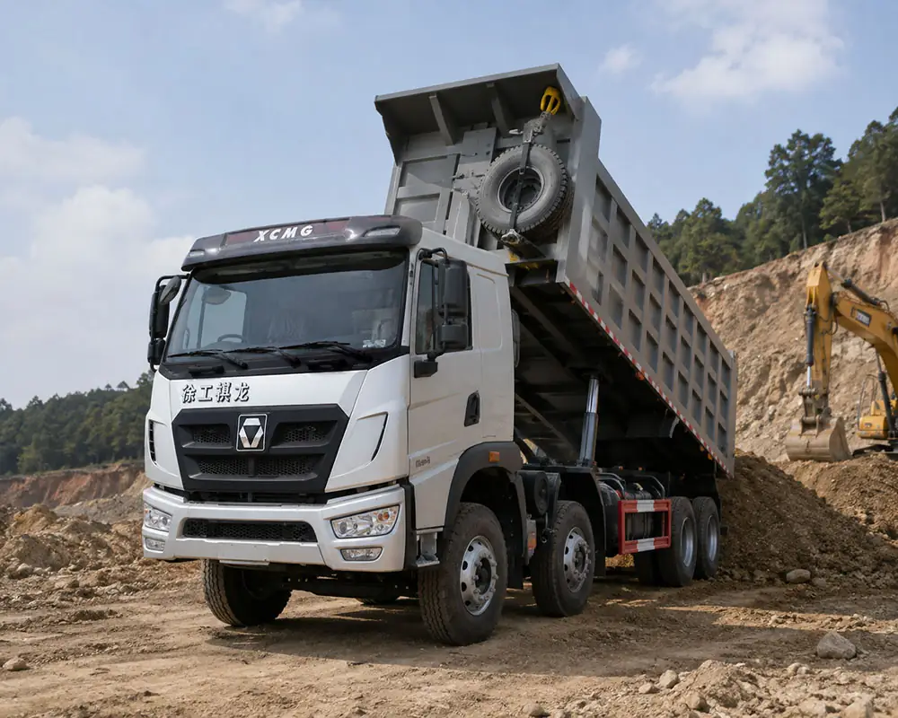 Side view of an XCMG Qilong 8x4 dump truck with its hydraulic system engaged, unloading aggregate at a quarry with an excavator in the background.