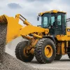 A powerful yellow XCMG ZL50GN 5-ton wheel loader discharging gravel onto a stockpile, showcasing its productivity and heavy-duty performance.